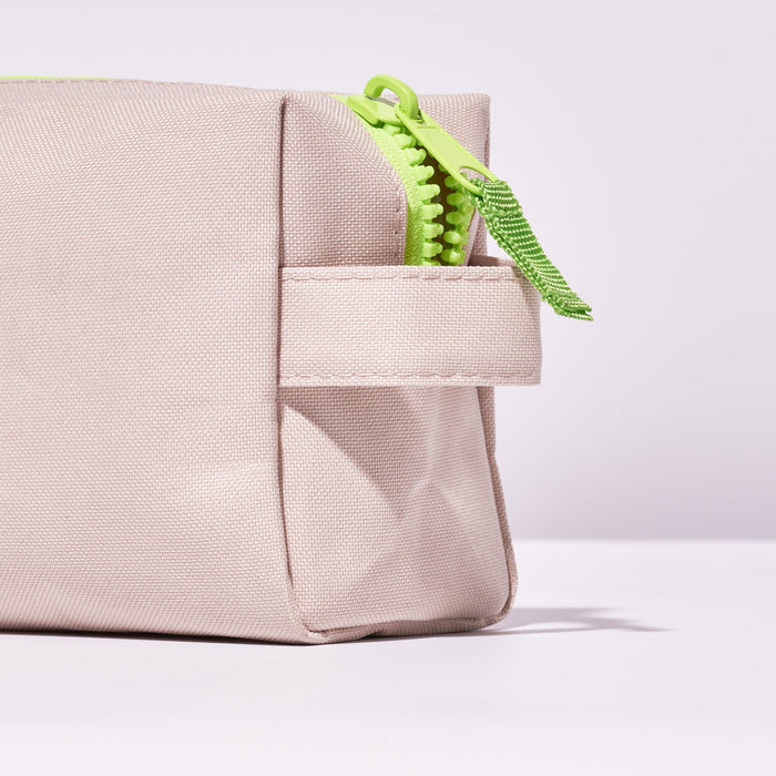 Close up of an end of Fussy's Recycled Washbag in pale pink with a lime green zip
