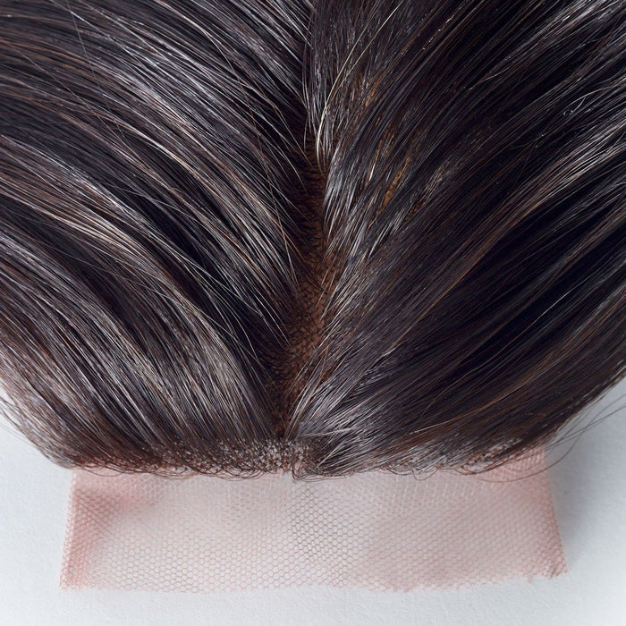 Close-up of dark brown hair on a light pink, sheer lace base for lace front wigs, highlighting the natural-looking hairline and parting.