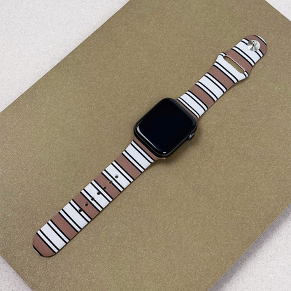 Smartwatch with a black screen and Retro Stripes Coconut Lane strap, displayed on a gold surface.