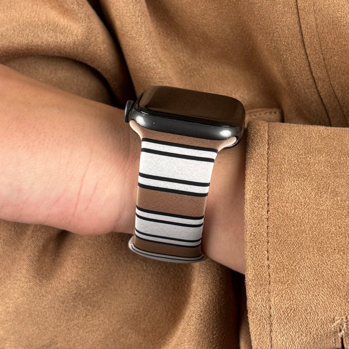 Retro striped Coconut Lane Apple Watch strap on wrist, paired with a tan coat.