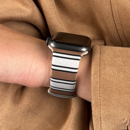 Retro striped Coconut Lane Apple Watch strap on wrist, paired with a tan coat.
