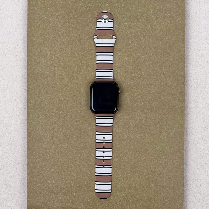 Coconut Lane Apple Watch strap with retro stripes on a textured beige surface.