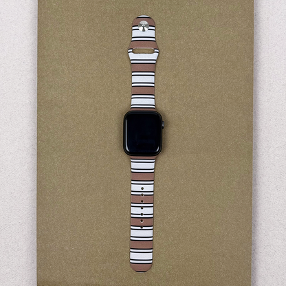 Coconut Lane Apple Watch strap with retro stripes on a textured beige surface.