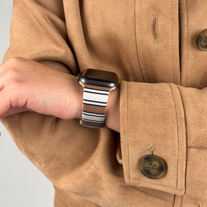 Coconut Lane Retro Stripes Apple Watch Strap in black and white stripes, worn with a tan coat.