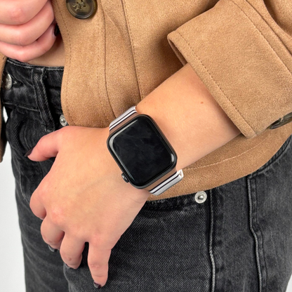 Coconut Lane Retro Stripes Apple Watch strap with colorful stripes, worn on wrist; tan jacket and black jeans visible.