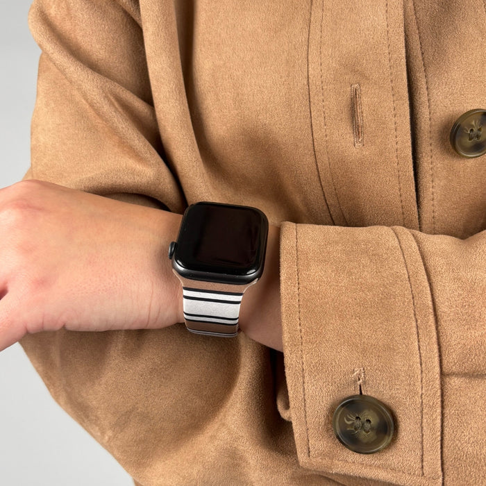 Black smartwatch featuring a Coconut Lane Retro Stripes strap, worn by someone in a tan coat.