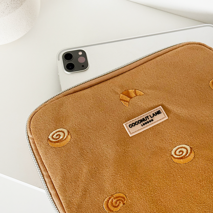 Suedette Croissant Club iPad sleeve in beige by Coconut Lane, partially covering a silver iPad on a white surface.