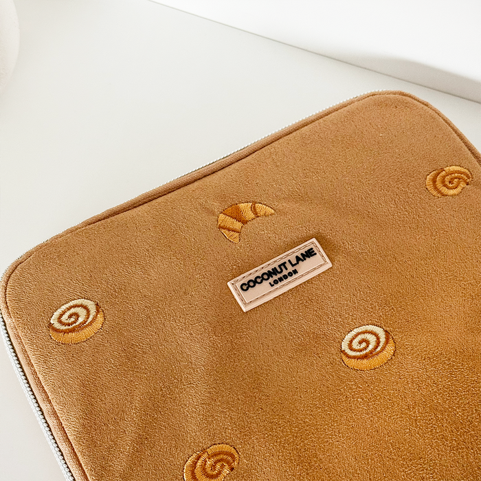 Tan suedette iPad sleeve with embroidered pastries and a Coconut Lane logo label at the center.