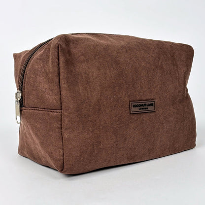 Chocolate brown suedette makeup bag with a front label, displayed against a plain background.