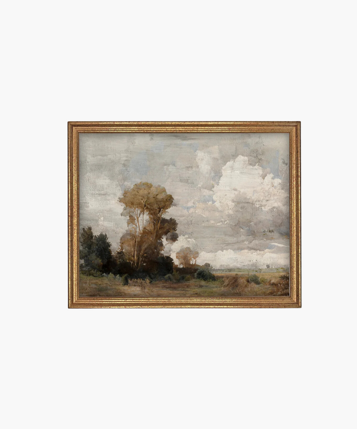 A framed landscape painting features tall trees on the left against a backdrop of expansive, cloudy skies. The scene conveys serenity and subtle drama. | Wildwood Home Co.