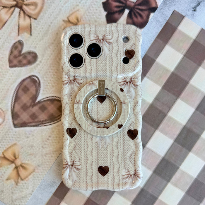 Sweater Weather Sweetheart MagSafe grip ring shown attached to the back of an iPhone with matching cream knit, bow, and heart print styling.