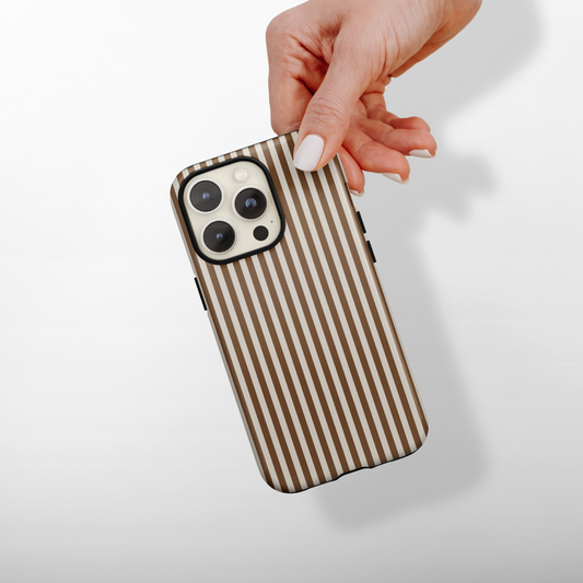 Hand holding a Coconut Lane Tough MagSafe phone case with chestnut stripes on a light background.