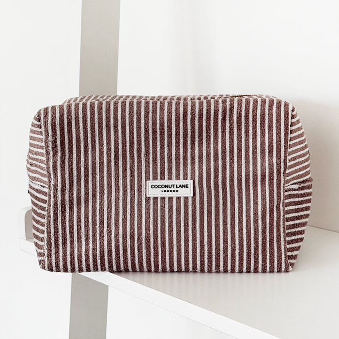 Chestnut striped makeup bag with towel texture displayed on a white shelf against a plain white background.