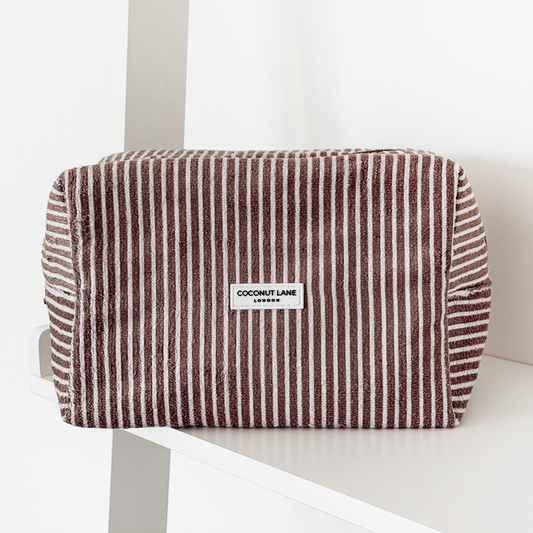 Chestnut striped makeup bag with towel texture displayed on a white shelf against a plain white background.