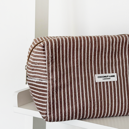 Chestnut striped towel makeup bag with zipper, by Coconut Lane, displayed on a white shelf.