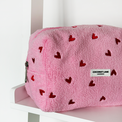 Pink pouch with red heart patterns on a white surface