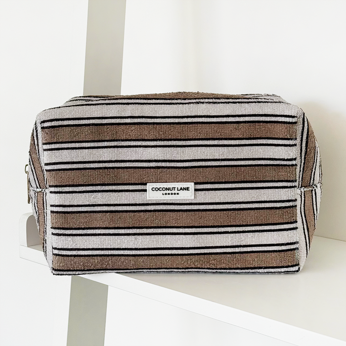 Terry cloth makeup bag with retro stripes pattern by Coconut Lane on a white shelf against a white background.