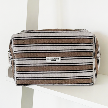 Terry cloth makeup bag with retro stripes pattern by Coconut Lane on a white shelf against a white background.