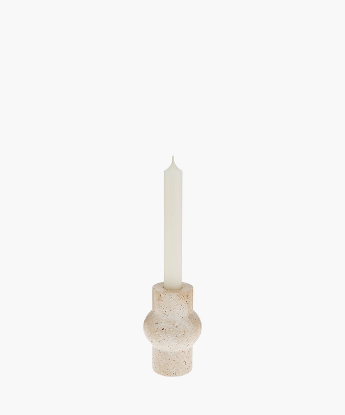 A tall white candle in a rounded, beige travertine stone holder with a textured surface. The minimalist design evokes a calm and serene atmosphere. | SW Home