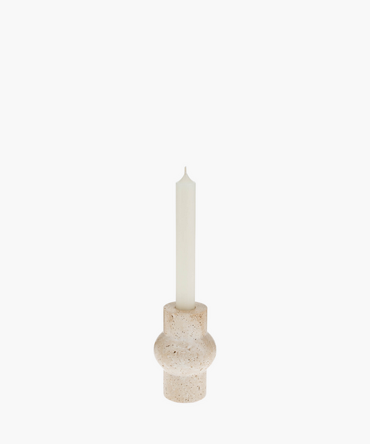 A tall white candle in a rounded, beige travertine stone holder with a textured surface. The minimalist design evokes a calm and serene atmosphere. | SW Home