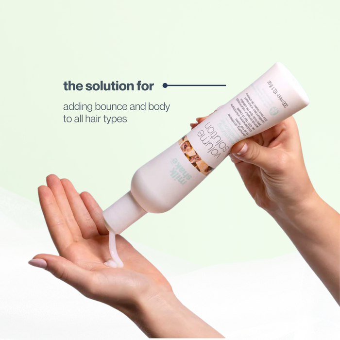 Hand holding a bottle of milk_shake  hair product with text on a light green background