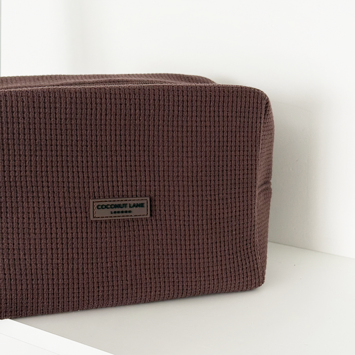Chocolate brown waffle-textured makeup bag by Coconut Lane on a white surface with a white background.