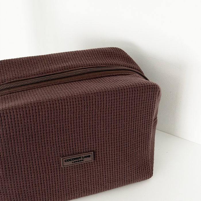Chocolate brown Coconut Lane waffle-textured makeup bag on a white surface.
