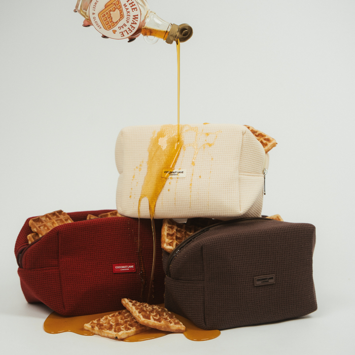 Chocolate brown waffle-textured makeup bag with syrup spills on a plain white background.