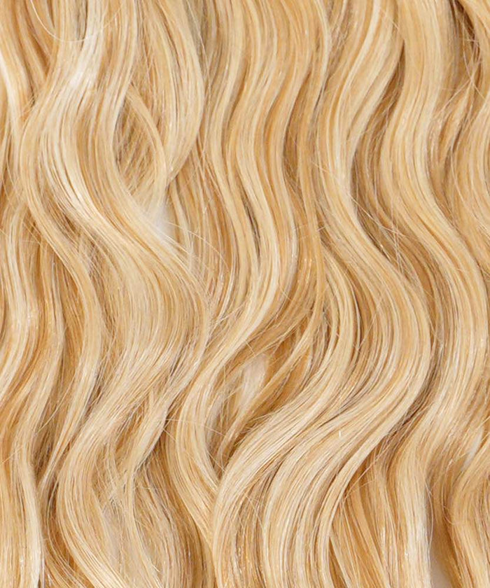Close-up of long, wavy Chocolate Brown  hair with a shiny, healthy look. Smooth strands highlight Perfect Locks extensions.#color_caramel-blonde-highlights-(24/27/613)