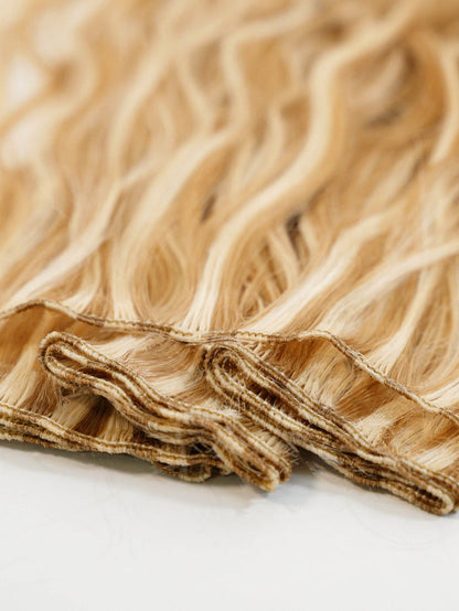 Close-up of Perfect Locks Wavy Hand-Tied Weft Rows (2oz) in Chocolate Brown , with layered, wavy extensions and visible wefts neatly stacked on a white surface.#color_caramel-blonde-highlights-(24/27/613)