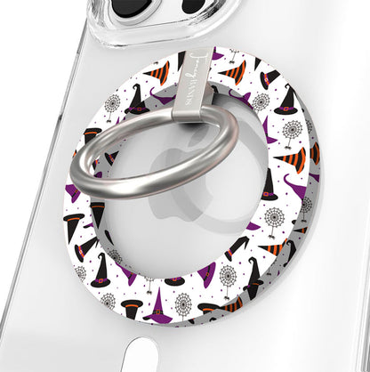 Witch Please Hold It Fancy MagSafe grip ring close-up on a clear iPhone case, showing the white ring scattered with purple, black and striped orange witch hats around the silver rotating ring.