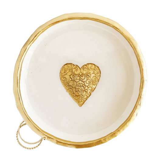A handcrafted ring dish with a gold heart-shaped design on a white background, with a gold rim.